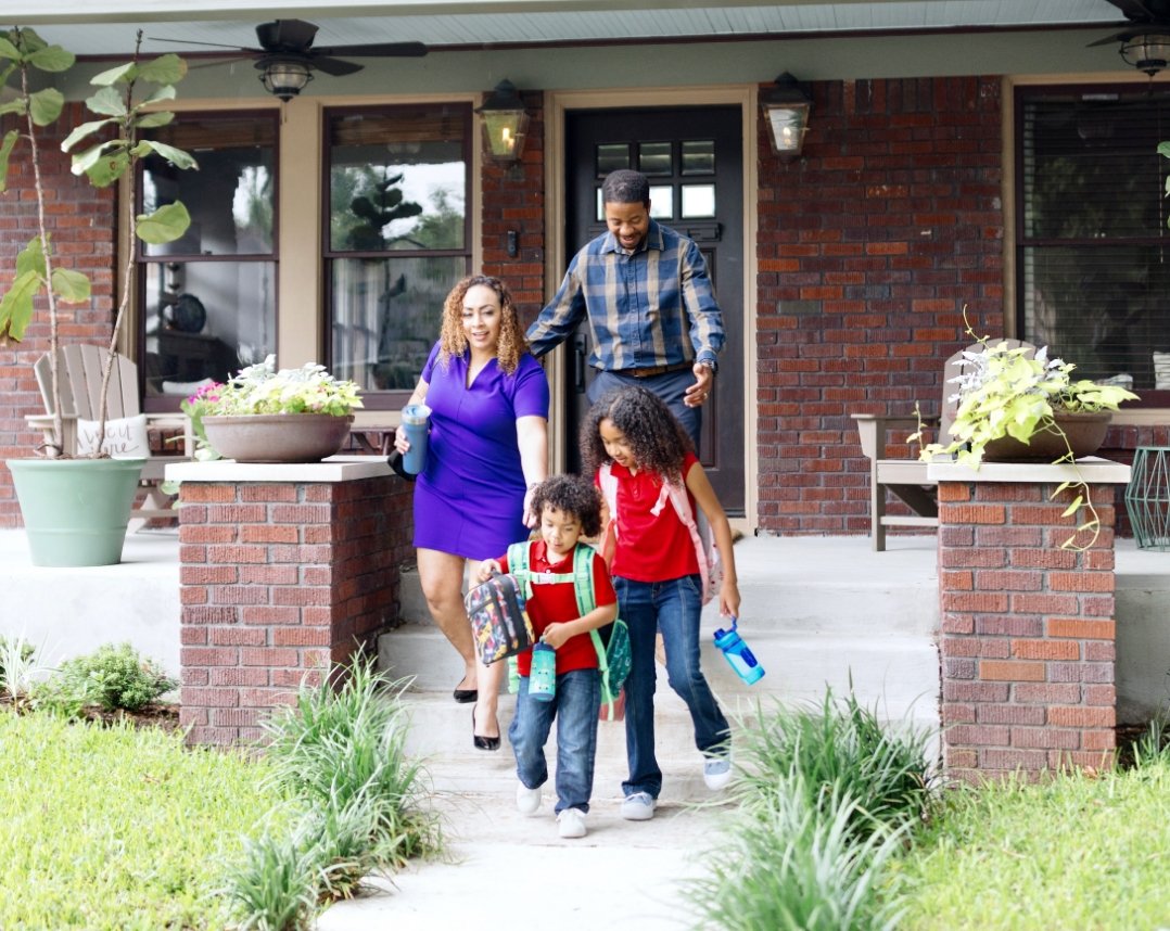 Parents and two small children leaving the house to go to school